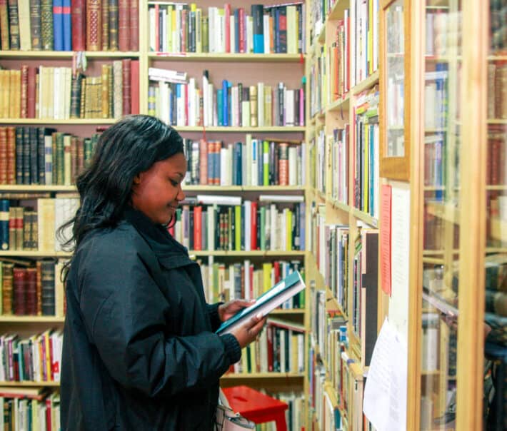 A student examining a book in a library.