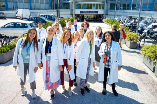 Students standing in white coats outside the hospital.