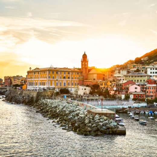 The city of Genoa along the waterfront at sunset.